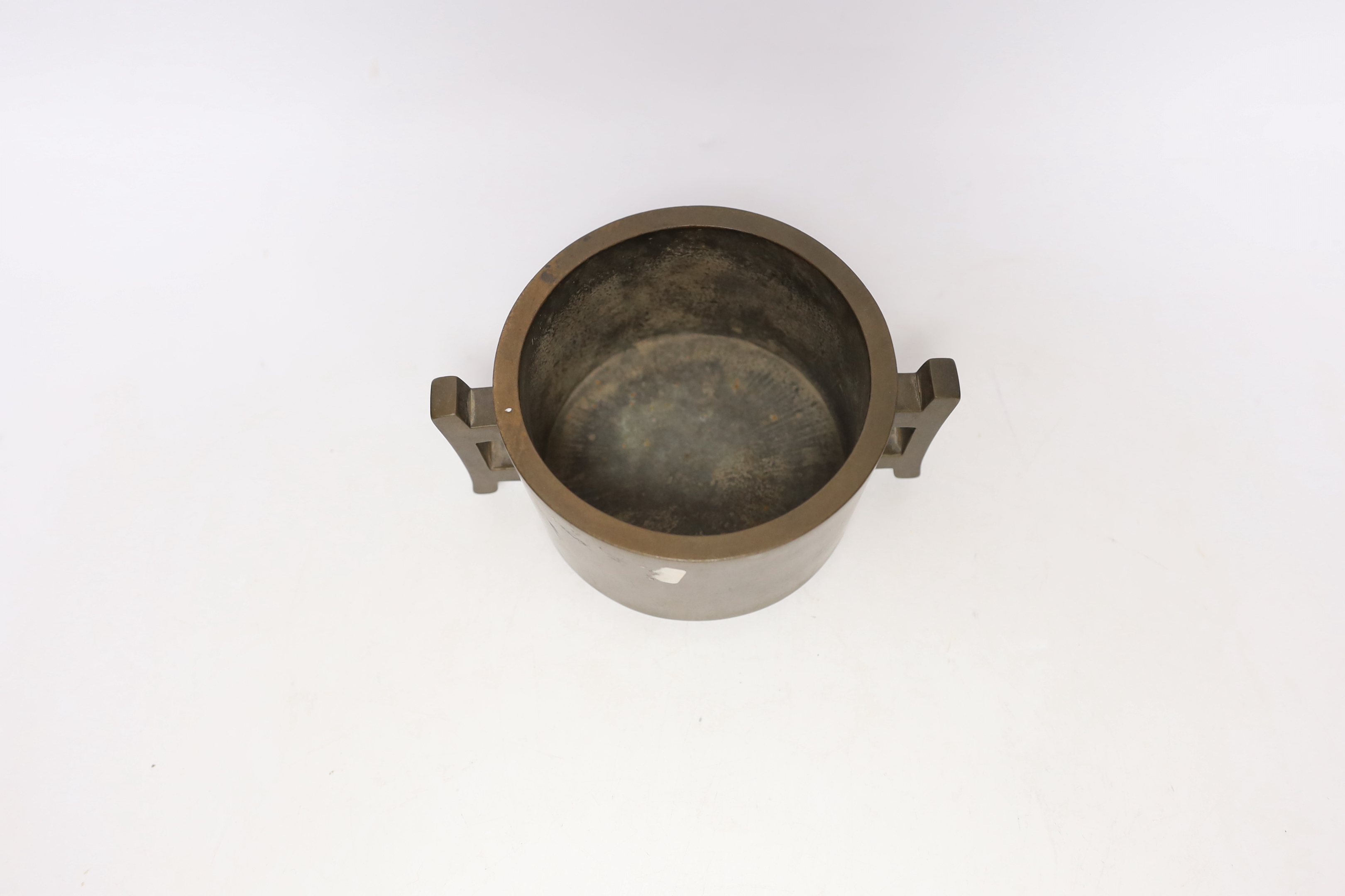 A Chinese bronze censer, of tapering cylindrical form, applied with a pair of trellis shaped handles, cast four character mark, 16cm wide